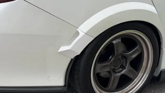 White winglet fitted behind the rear wheel of a white Honda Civic with bronze five-spoke wheels