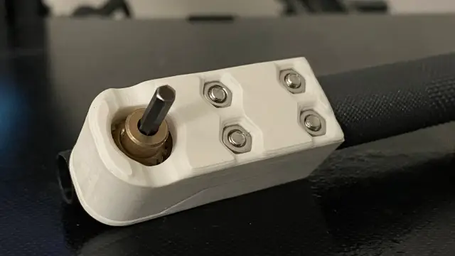 White 3D-printed driver head with a short hex pin sticking out at a right angle from a brass bushing, held together with four screws and nuts