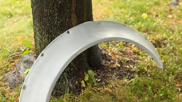 Grey full-size printed fender flare standing against a tree trunk on grass